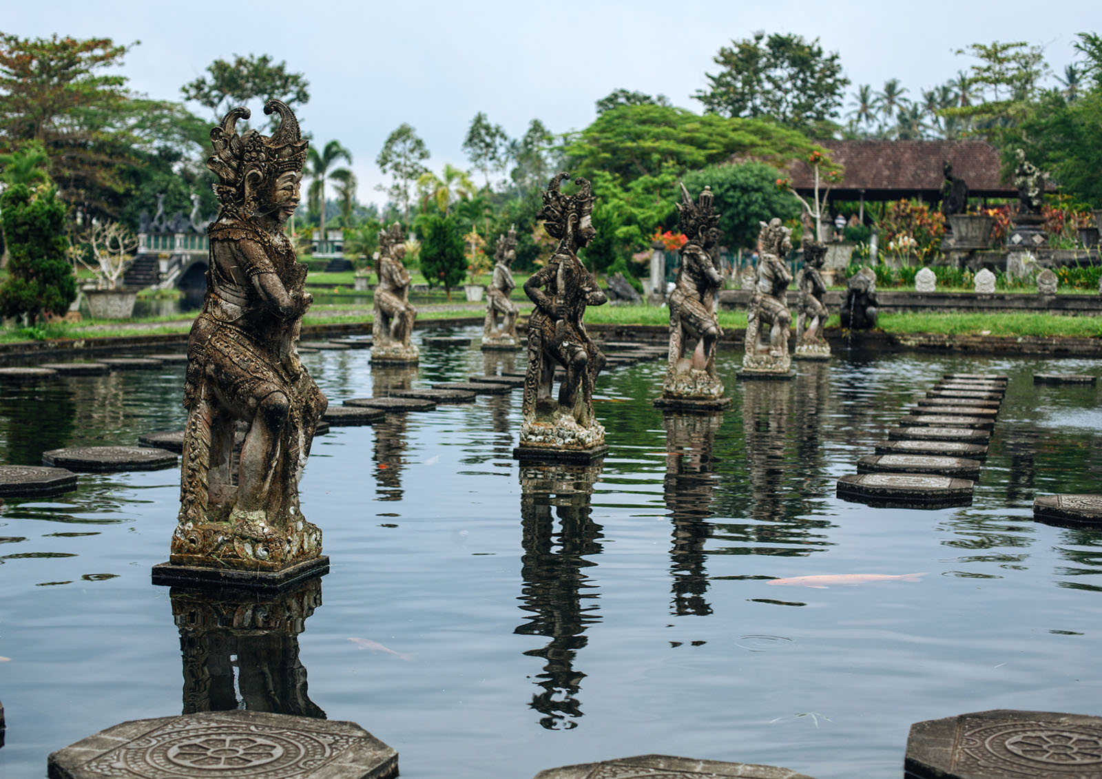 Tirta Gangga water palace with stone statues, koi-filled pools, and lush gardens in East Bali